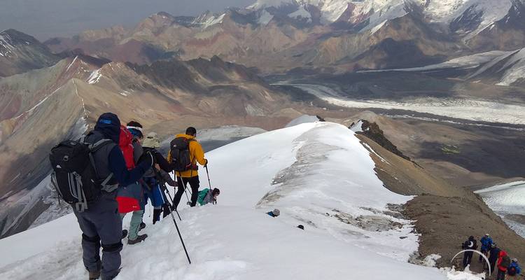 Randonneurs traversant une crête de montagne enneigée.