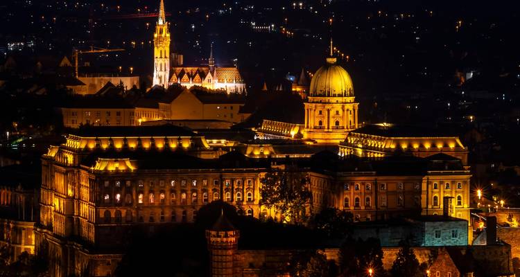 Cityscape at night with illuminated historic buildings.