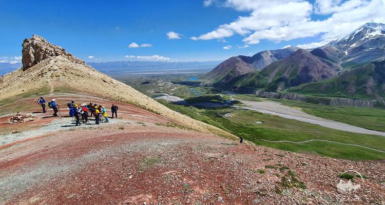 Groupe de personnes faisant de la randonnée sur une crête de montagne avec une vue sur une vaste vallée.