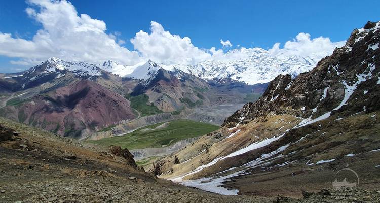 Montagnes enneigées avec un premier plan rocheux et un ciel dégagé.