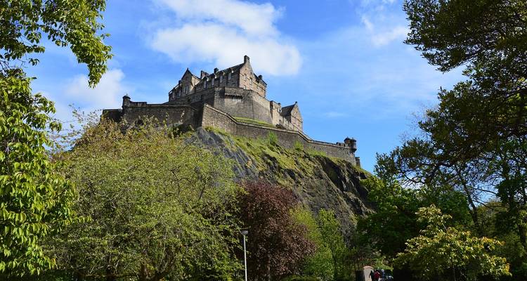 Château historique sur une colline avec une végétation luxuriante.