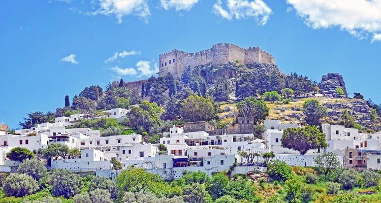 Maisons blanchies à la chaux en contrebas d'une ancienne forteresse sur une colline.