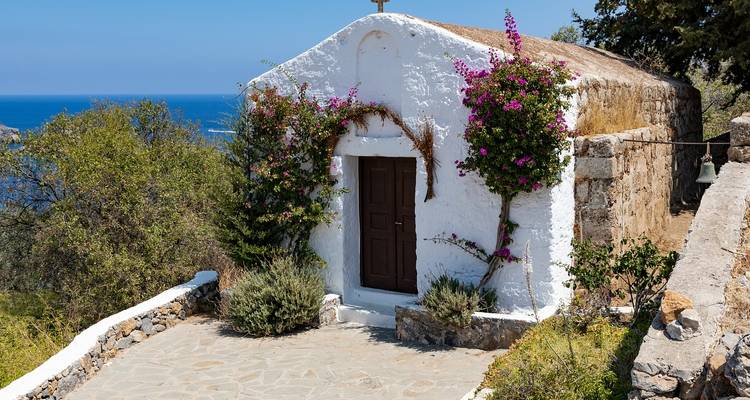 Charmante petite chapelle blanche avec des fleurs surplombant la mer.