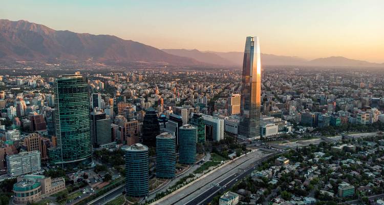 Aerial cityscape of Santiago with skyscrapers and mountains during sunset.