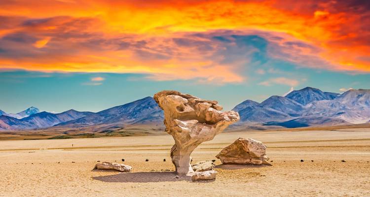 Unique rock formation in a desert landscape with a vibrant sunset.