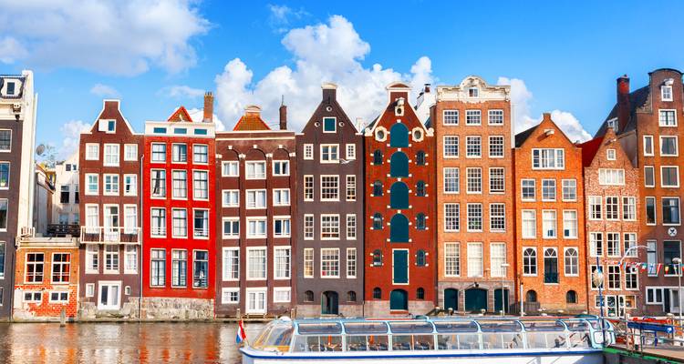 Rangée de maisons colorées et étroites le long d'un canal.