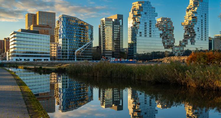 Gratte-ciel modernes avec reflets dans l'eau au coucher du soleil.