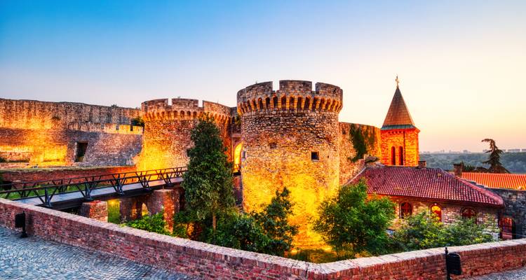Forteresse de pierre historique illuminée au coucher du soleil.