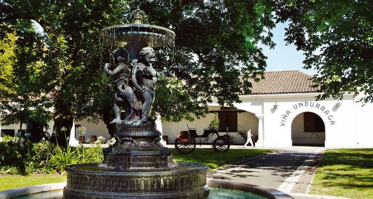 Fontaine avec chérubins devant un bâtiment historique de cave vinicole.