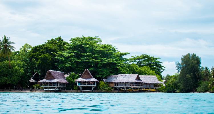 Huttes de chaume au bord de l'eau sur une île luxuriante.