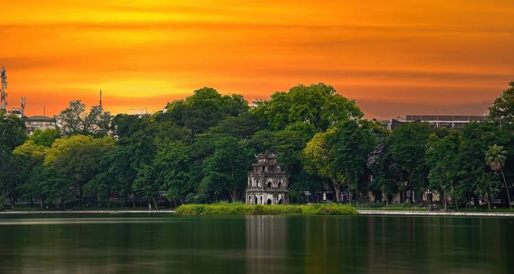 Atardecer sobre el Lago Hoan Kiem con la Torre de la Tortuga recortada contra un cielo naranja