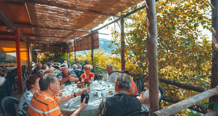 Groupe de personnes dînant en plein air sous un auvent.
