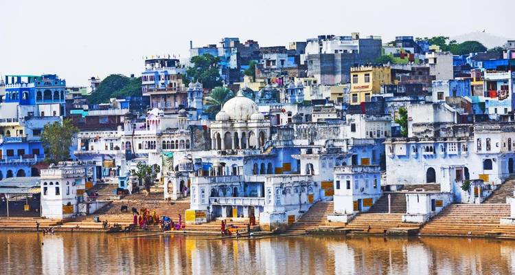 Vista de una ciudad junto al agua con ghats históricos y gente bañándose.