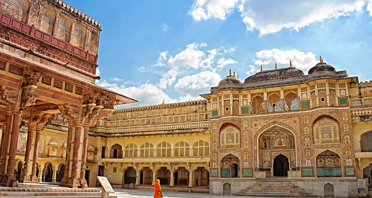 Un patio de palacio con arcos ornamentados y un visitante con atuendo tradicional.