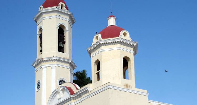 Twin bell towers of a colonial-style church under a clear blue sky.
