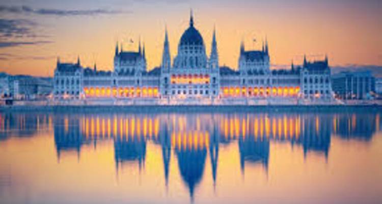 Bâtiment se reflétant dans l'eau au coucher du soleil, couleurs vives.