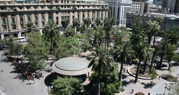 Plaza pública en Santiago con personas caminando entre palmeras.