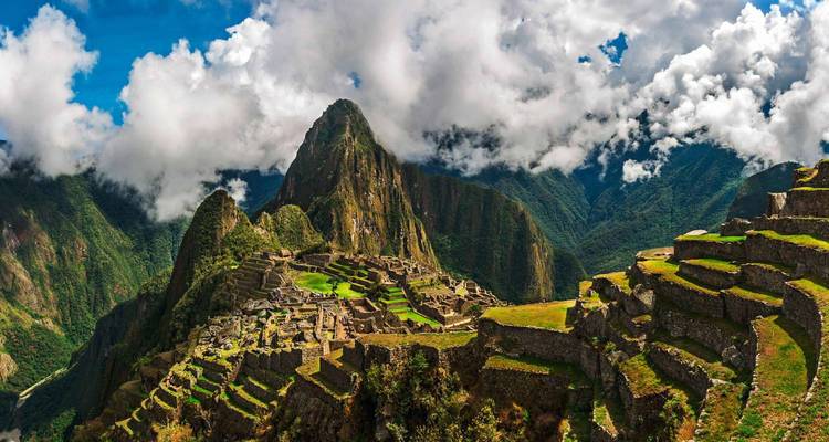 Iconic view of Machu Picchu with lush greenery and clouds.