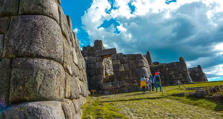 Tourists exploring large stone ruins under a dynamic sky.