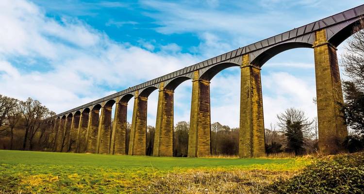 Grand viaduc traversant un champ avec un ciel bleu.
