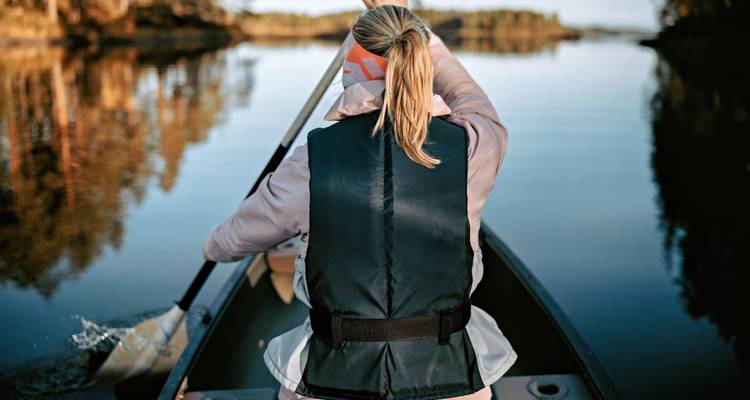 Personne pagayant en canoë sur un lac calme.