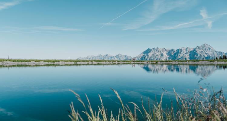 Ein ruhiger See mit Bergen, die sich im stillen Wasser spiegeln.