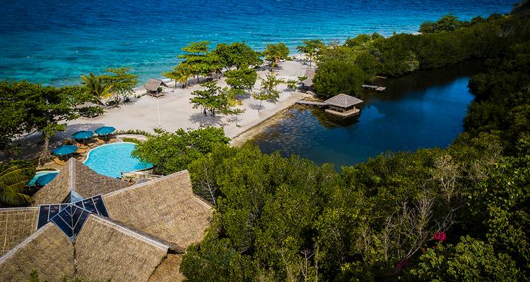 Vista aérea de un resort de playa rodeado de exuberante vegetación y océano en las Filipinas.