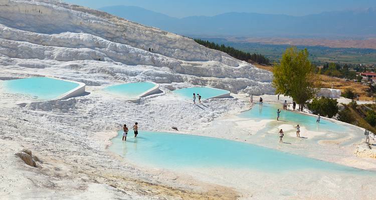 Thermal pools of Pamukkale with people wading in the water.
