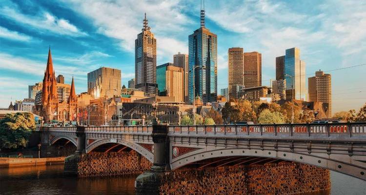 Cityscape with modern buildings and a bridge over a river.