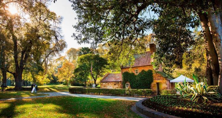 Historic cottage amidst a garden with autumn foliage.