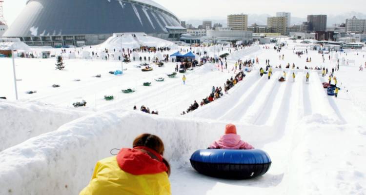 Winter sports activity with people sledding on snowy hills.