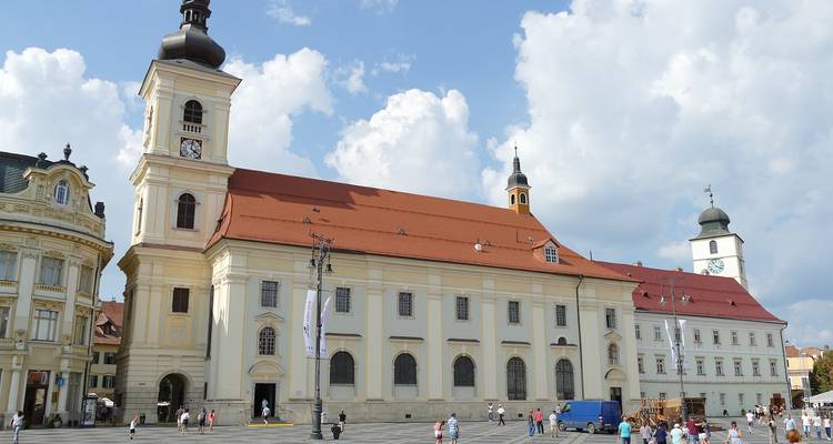 Grand bâtiment historique avec tours d'horloge sur une place publique.