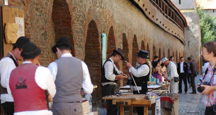 Des gens vêtus de costumes traditionnels dans un marché artisanal en plein air.