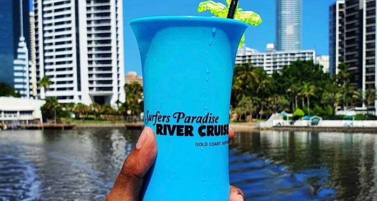 Mano sosteniendo una bebida con el horizonte de la ciudad de fondo.