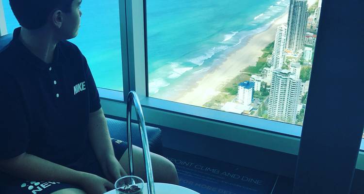 Una persona mirando hacia la playa desde un punto de vista elevado en un rascacielos.