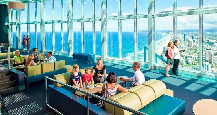 Diferentes grupos de personas cenando y disfrutando de la vista desde un rascacielos.