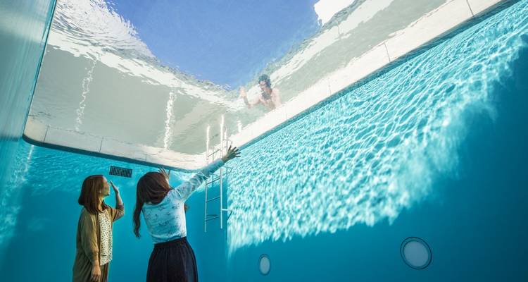 Des personnes observant une installation artistique qui semble se trouver sous l'eau.