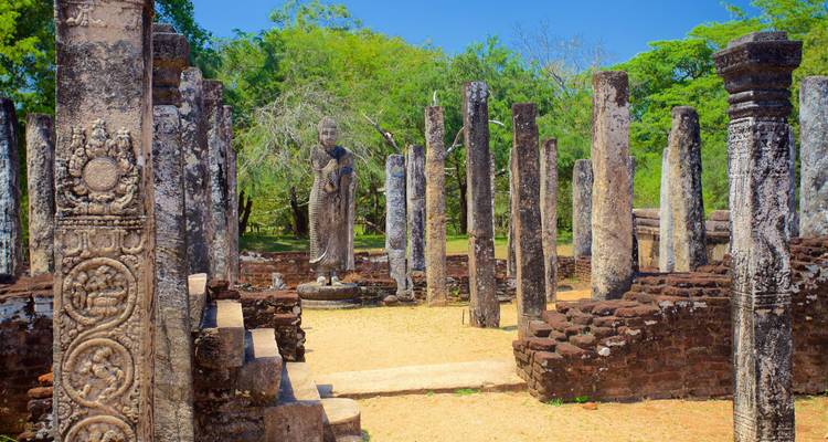 Ruins of ancient city with standing Buddha statue.