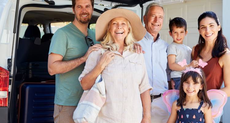 A happy family posing in front of a vehicle ready for a journey.
