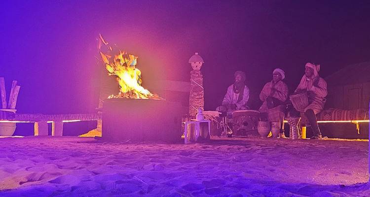 Night scene with people sitting around a campfire in a desert setting.