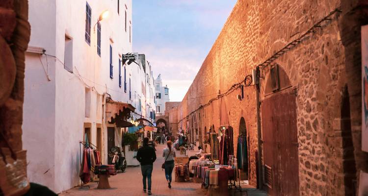Pedestrian street with shops and historic stone walls.