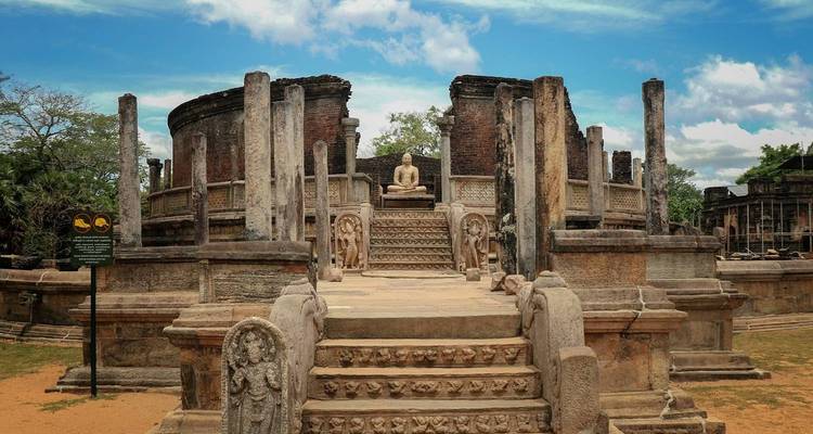 Ruines anciennes avec une statue de Bouddha assis au milieu de sculptures ornementées.