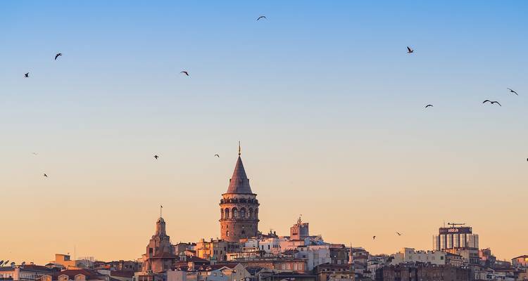 Galata Toren met vogels in de lucht tijdens zonsondergang.