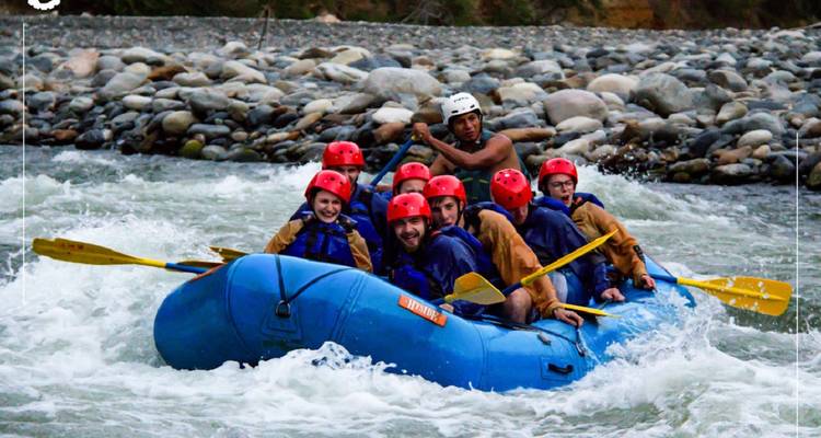 Group of people in a raft navigating river rapids.