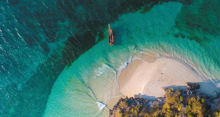 Vista aérea de un mar turquesa que rodea una pequeña isla arenosa.