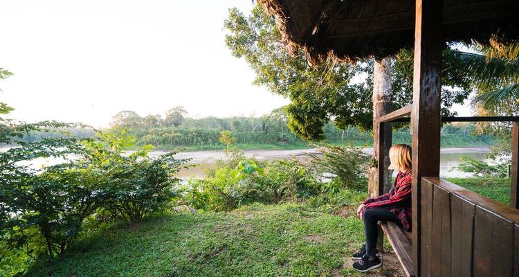 Personne assise sur un porche surplombant un espace verdoyant luxuriant.