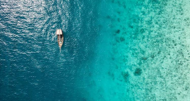 Single boat in a vast stretch of turquoise water.
