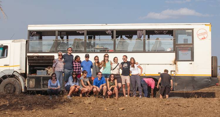 Group posing in front of a large tour vehicle.