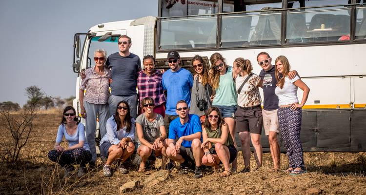 Group of people posing in front of a large tour vehicle.