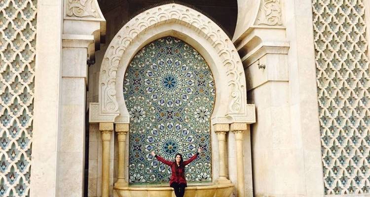 Une femme posant devant une architecture marocaine complexe.